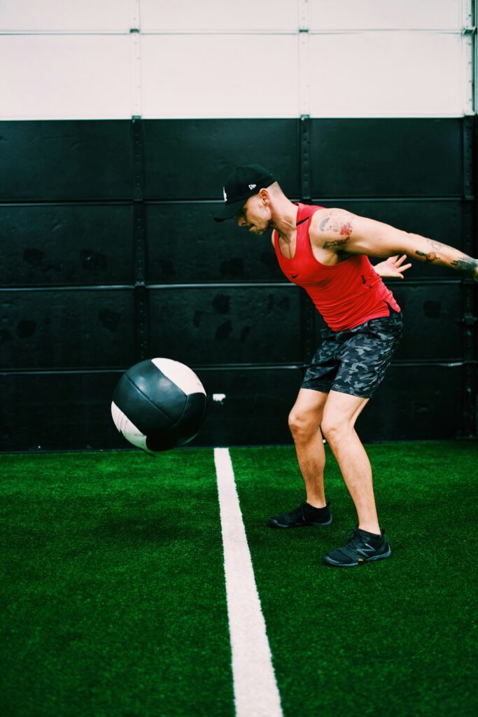 Adult throwing a medicine ball against a wall with explosive movement. Athletic and focused expression.